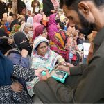 A retailer is scanning women's thumb by a machine at the Company Bagh Center to distribute money under the Benazir Income Support Program