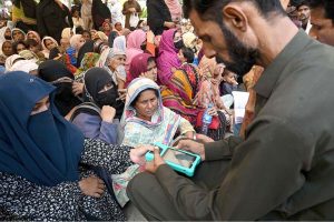 A retailer is scanning women's thumb by a machine at the Company Bagh Center to distribute money under the Benazir Income Support Program