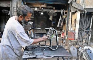 A painter paints motorcycle body parts at Akbar Road to earn his livelihood.