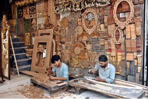 Craftsmen are busy carving intricate designs on wood in their workshop.
