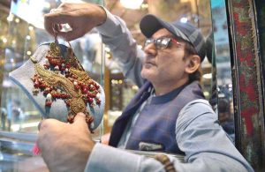 A vendor displaying gold jewelry to attract the customers in his shop at Sarafa Bazaar.