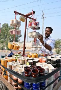 A vendor arranges and displays teacups on his handcart to attract customers.