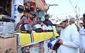 A vendor sells motorcycle helmets at his roadside stall as traffic police strictly enforce a heavy fine on motorcyclists riding without helmets at Shaheen Chowk.