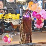 A woman displaying colorful lighting balloons to attract the customers at Latifabad