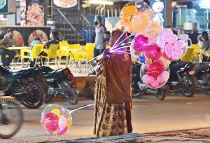 A woman displaying colorful lighting balloons to attract the customers at Latifabad