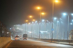 A night view of the city covered in heavy smog causing low visibility on roads.
