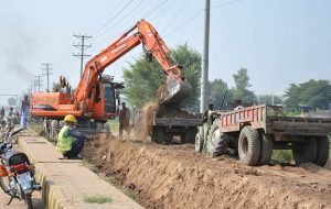 Workers loading mud with the help of a machine on tractor trolley after digging during the construction work in the city.