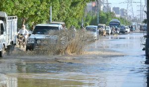Commuters wade through stagnate rainwater in Korangi, a day after heavy rains lashed the city.