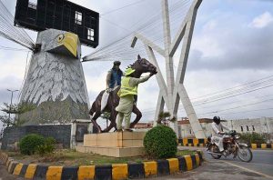 PHA staffer busy in cleaning statue of horse at Lahore Bypass.