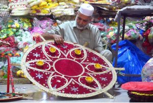 An old man busy in giving final touches to handmade mehndi function related item at his workplace near Fawara Chowk.