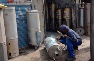 A worker welds while making geysers at his shop as demand rises with the onset of the winter season.