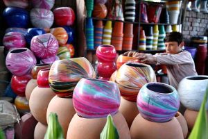 A young vendor arranges and displays colorful pots for plants to attract the customers at a local nursery.
