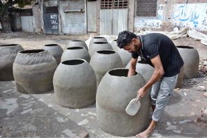 An artisan busy in preparing traditional clay oven (tandoor) at his workplace.
