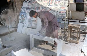A worker is busy polishing and finishing a marble slab with the help of a machine at his workplace.