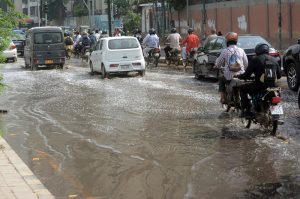 Commuters wade through stagnant sewerage water near Frere Police Station, causing traffic disruption and inconvenience to pedestrians.