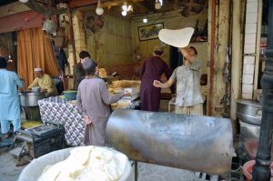Vendor preparing traditional 'chapati Naan' for a customer at Fawara Chowk.