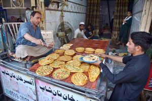 Vendor preparing traditional 'chapati Naan' for a customer at Fawara Chowk.