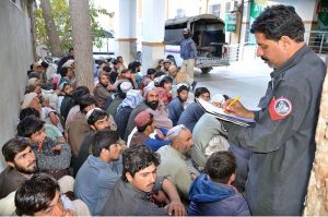 Police personnel registers the names and details of Afghan nationals detained by the district administration for residing illegally