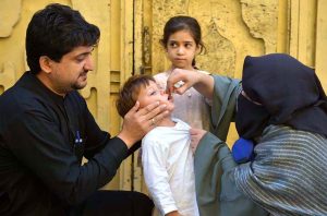 Lady health worker administering polio drops to a child during anti-polio vaccination campaign in the Provincial Capital