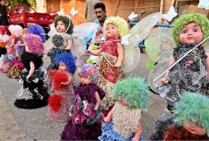 A young vendor arranging and displaying toys on footpath to attract the customers at Girls College Road