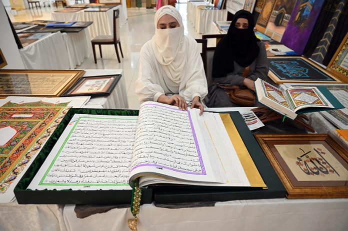 Women displaying Islamic calligraphy artwork during the 3rd Pakistan Hajj & Umrah Exhibition 2025 at Pak-China Friendship Centre