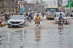 Vehicles and motorcyclist carefully navigate through rainwater after overnight rain turned city roads into rivers.