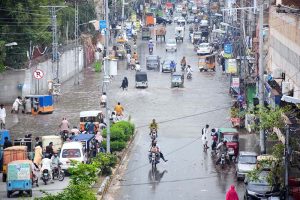 Vehicles and motorcyclist carefully navigate through rainwater after overnight rain turned city roads into rivers.
