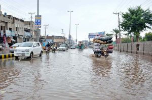 Vehicles and motorcyclist carefully navigate through rainwater after overnight rain turned city roads into rivers.