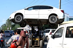 Traffic Police personnel are removing illegally parked vehicles from the road using lifter.