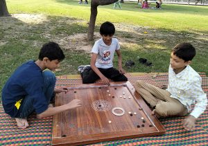Youngsters playing carom board during the sports competitions organized by the Walled City of Lahore Authority at Shalimar Bagh