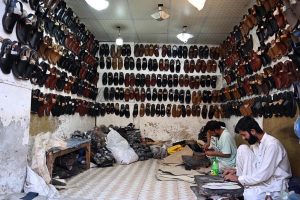 Cobbler preparing traditional shoes (Peshawari Chappal) to the customers at his workplace in the Provincial Capital