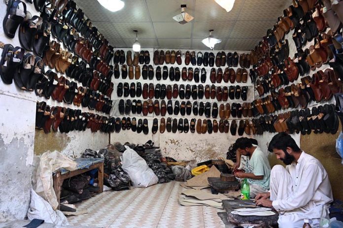 Cobbler preparing traditional shoes (Peshawari Chappal) to the customers at his workplace in the Provincial Capital