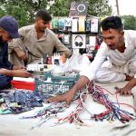A vendor arranging and displaying mobile phone accessories to attract the customers at his roadside setup in the City