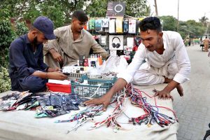 A vendor arranging and displaying mobile phone accessories to attract the customers at his roadside setup in the City