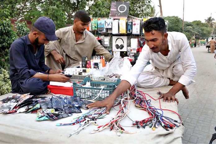 A vendor arranging and displaying mobile phone accessories to attract the customers at his roadside setup in the City