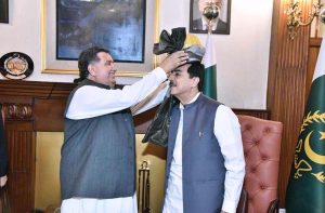 Chairman Pakistan Red Crescent Khyber Pakhtunkhwa, Farzand Ali Wazir presenting a traditional turban to Acting President Syed Yousuf Raza Gilani at Governor House.