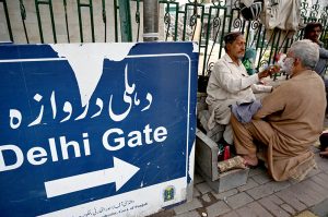 A barber busy in shaving his customer on footpath at the Dehli Gate in the Provincial Capital.