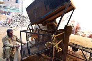 A worker feeding wood into a roasting machine to prepare peanuts at a local workplace on Lehtrar Road in the Federal Capital.