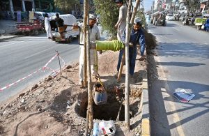 Labourers are busy digging a hole and removing soil to install an electric pole at Khana Pul