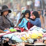 People selecting and purchasing used clothes along the roadside at Bagh Sardaran area in the city