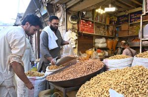 A vendor sells peanuts to customers at his shop in Ganj Mandi.