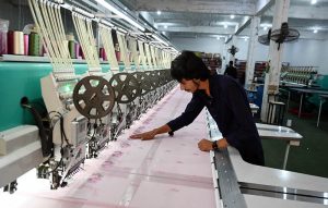 A worker adjusts an embroidery machine while designing fabric at a factory near Tarlai area in the Federal Capital.