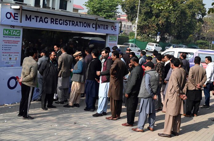 “People stand in a queue to install E-tags/M-tags for their vehicles at Kachnar Park