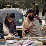 Girls browse and buy old books on stall at Mall Road near Urdu Bazar
