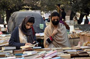 Girls browse and buy old books on stall at Mall Road near Urdu Bazar