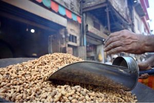 A vendor sells peanuts to customers at his shop in Ganj Mandi.