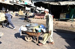 An elderly vendor pushes a wheelbarrow loaded with rice at the vegetable market in the Federal Capital.