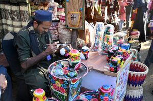An artisan paints truck art on different display tools at Ten-Day annual folk festival “Lok Mela 2025” at Lok Virsa