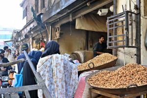 A vendor sells peanuts to customers at his shop in Ganj Mandi.