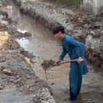 Laborer busy digging for installing pipelines on main commercial market road in the city